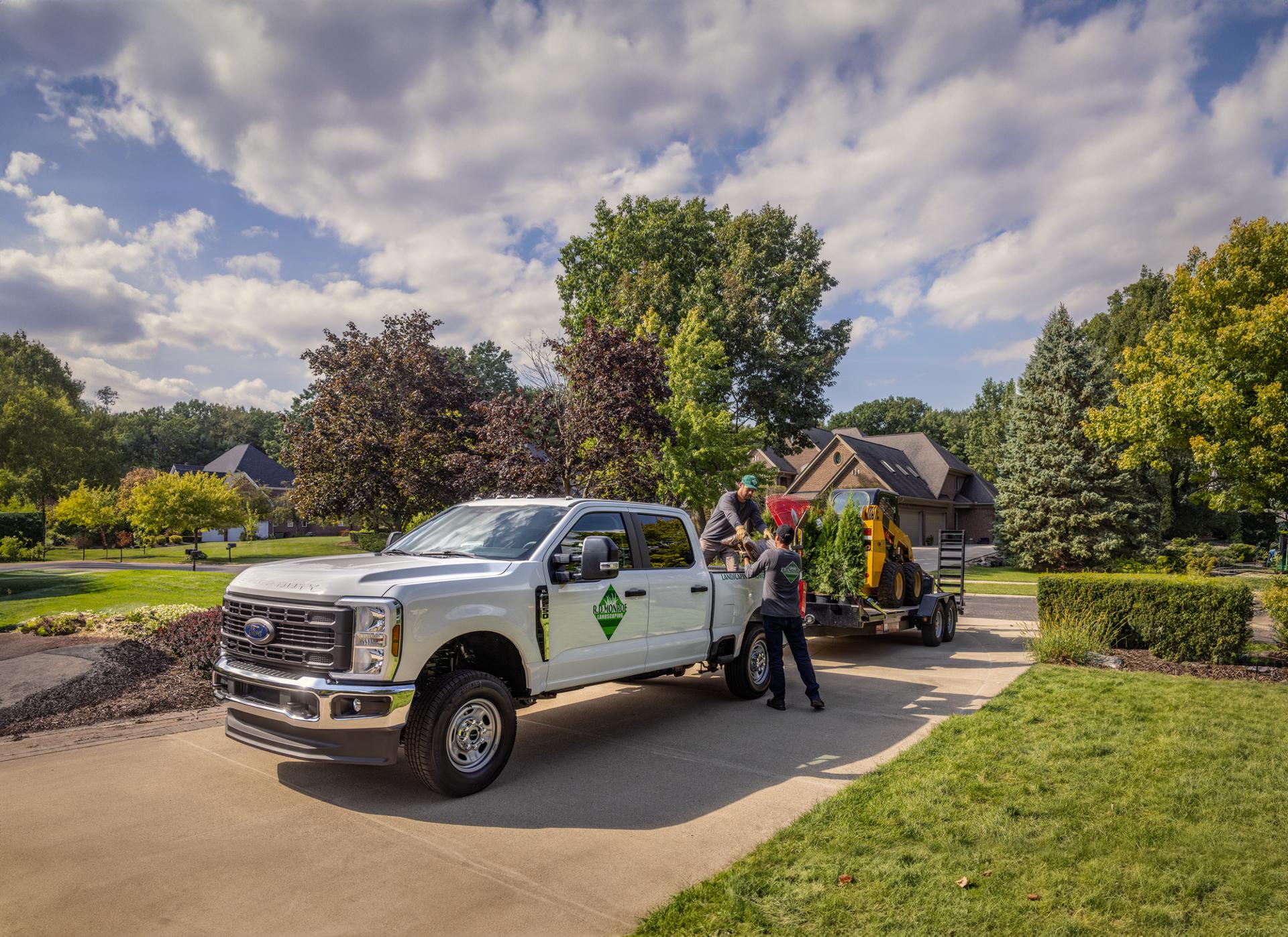 2026 Ford Super Duty® F-250® XLT parked in a residential driveway towing a trailer with lawnscaping equipment