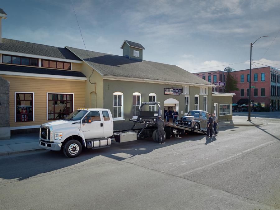 Une personne entrant dans le Ford F-650 2025 à cabine double avec plateau à recul et camion de remorquage en blanc Oxford