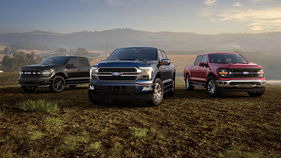2026 Ford F-150® Lariat®, F-150 Lightning®, and Platinum® models parked on a desert plain at dusk