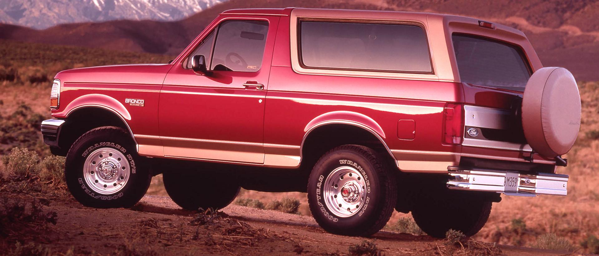 A red 1994 Ford Bronco® model parked overlooking a mountainous landscape