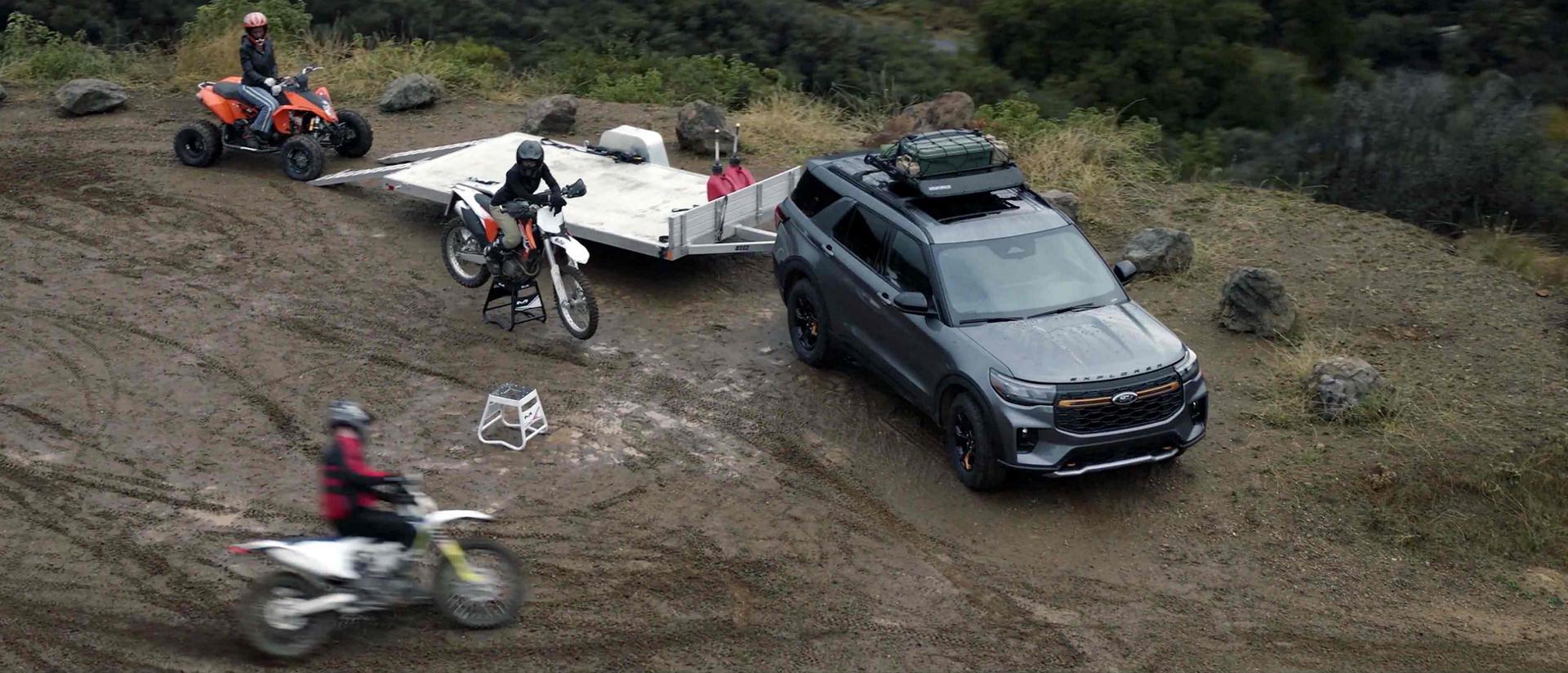 People using dirt bikes and an ATV near a 2026 Ford Explorer® Tremor® SUV