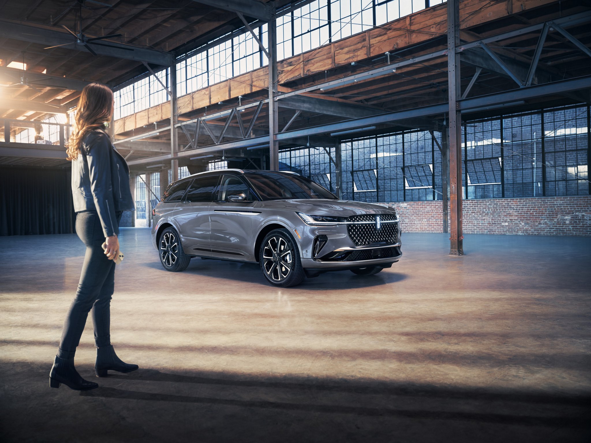 A smartphone is being held in a woman’s hand as she walks toward a 2025 Lincoln Nautilus SUV