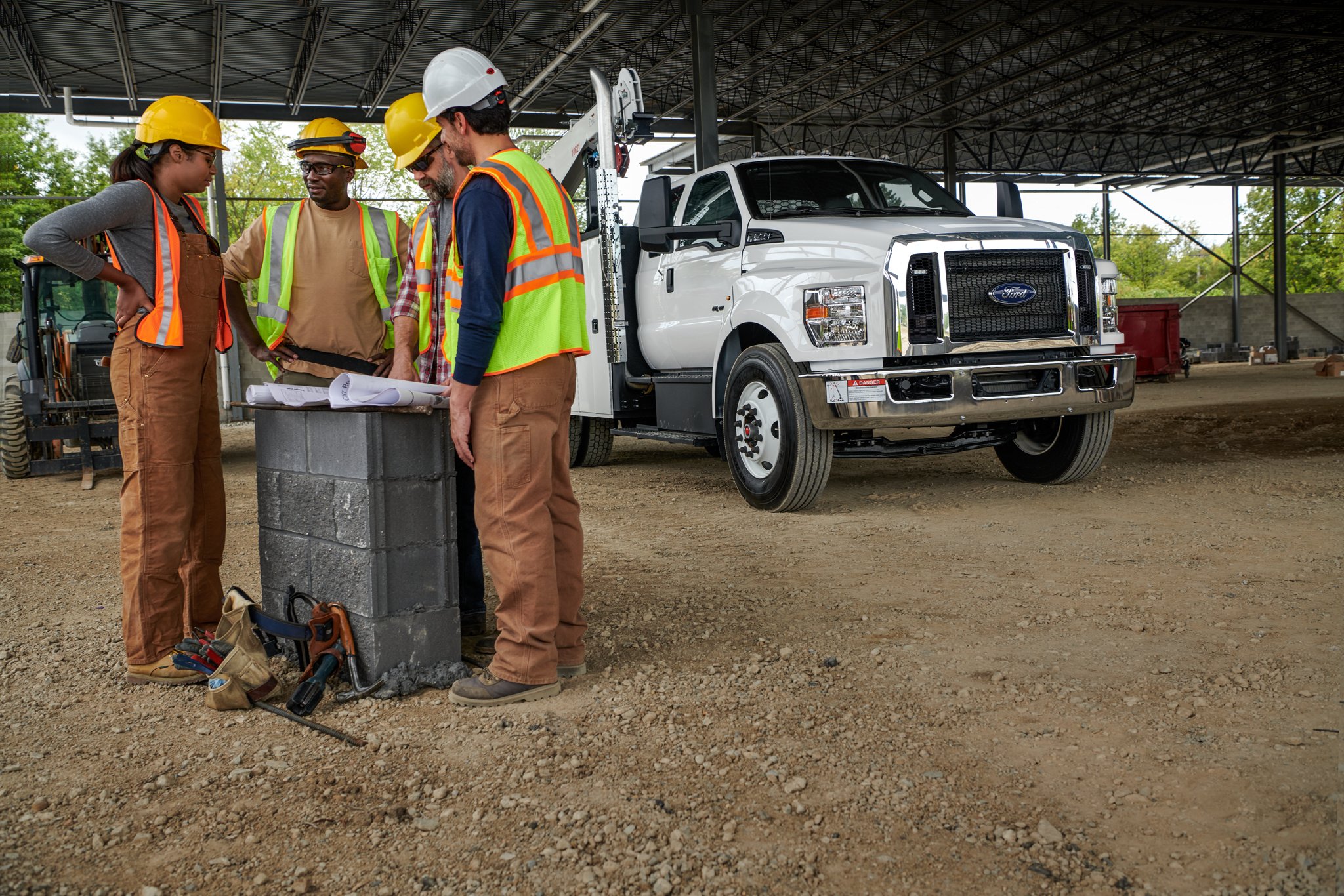 Travailleurs rassemblés près d’un Ford F-750 2025 en blanc Oxford à cabine double aménagé en camion de mécanicien en arrière-plan