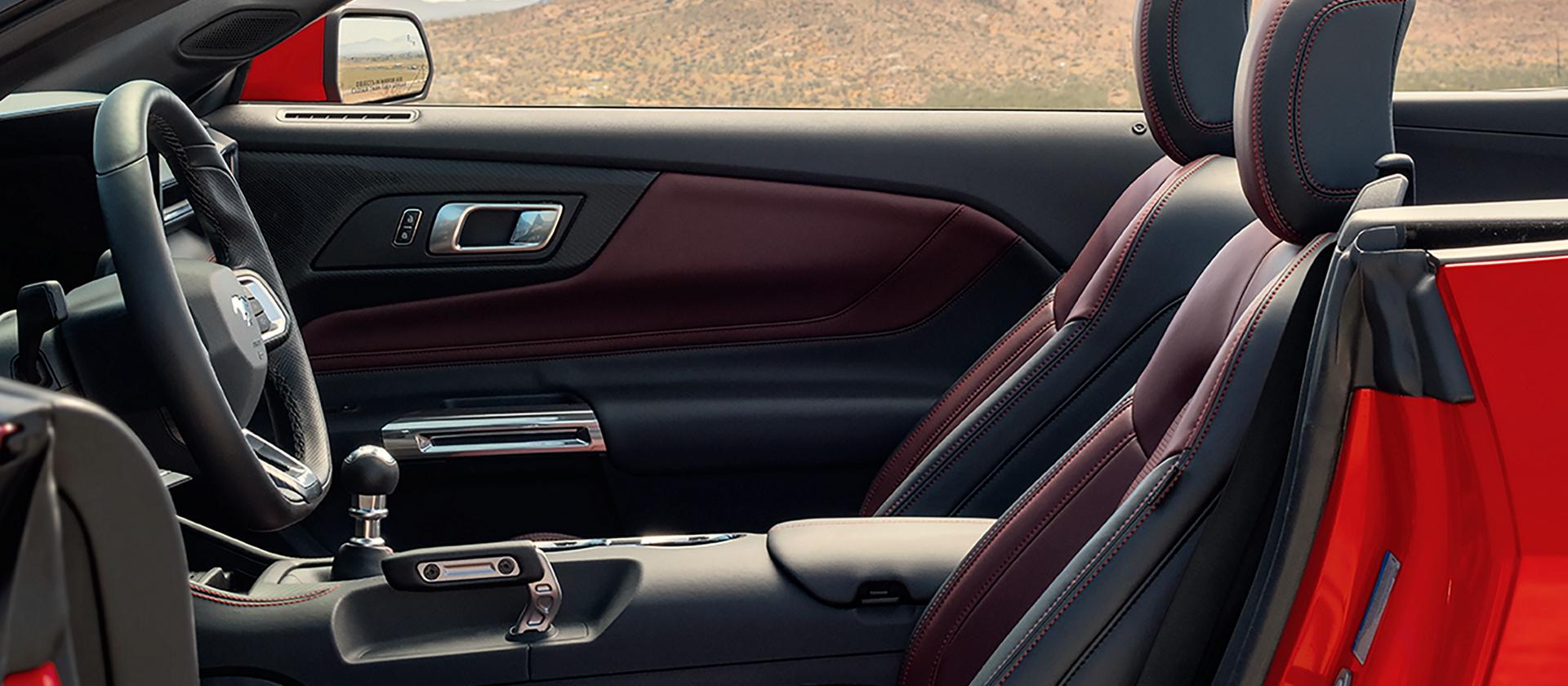 Parked 2026 Ford Mustang® convertible with the driver's side door open showing the available Carmine Red interior