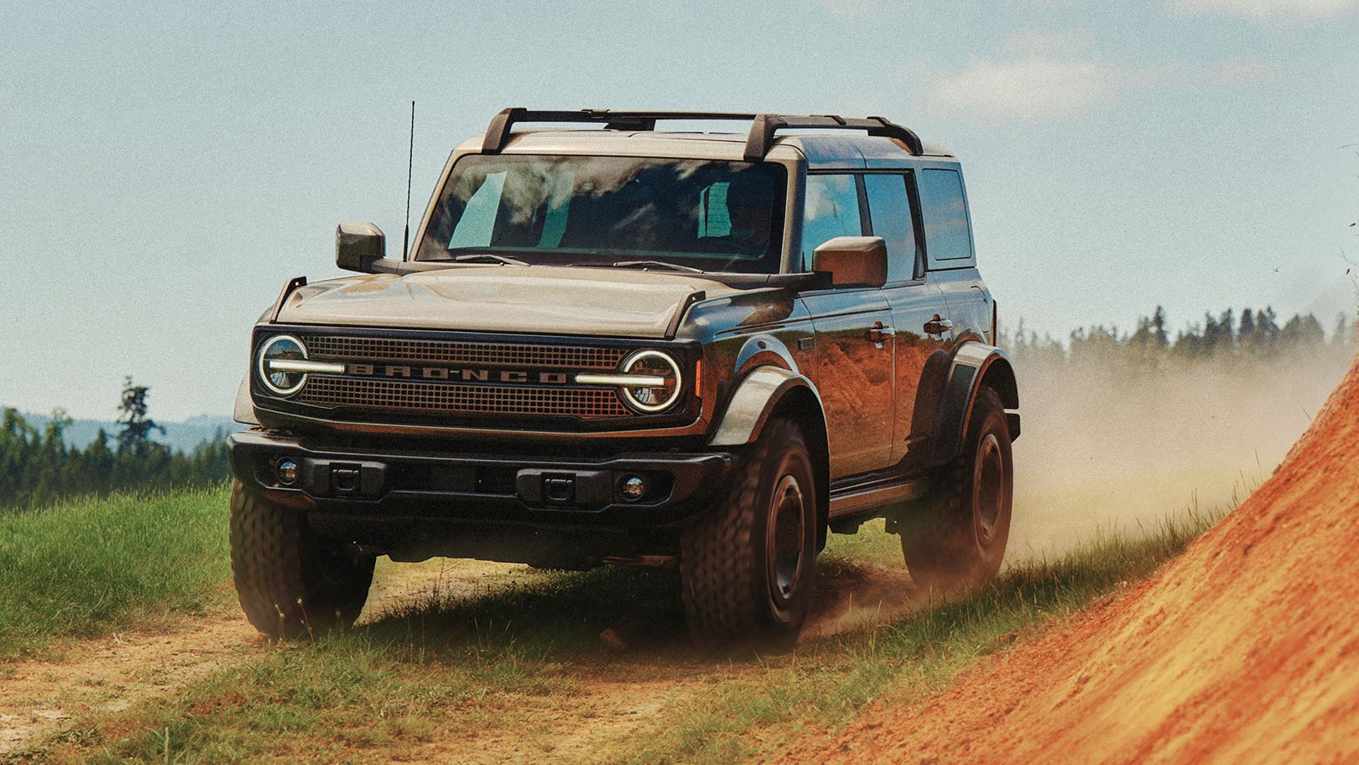 A 2027 Ford Bronco® Filson SUV being driven on a dirt trail near a hillside