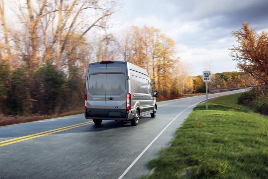 Rear view of a 2025 Ford Transit® van being driven down a road