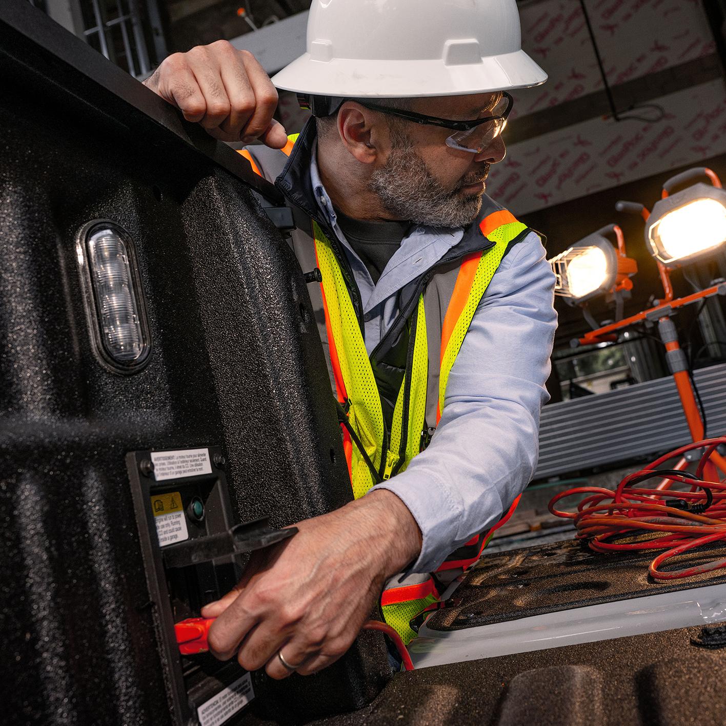 A worker plugs into the Pro Power Onboard™ outlet in the bed of a 2026 Ford Super Duty® truck