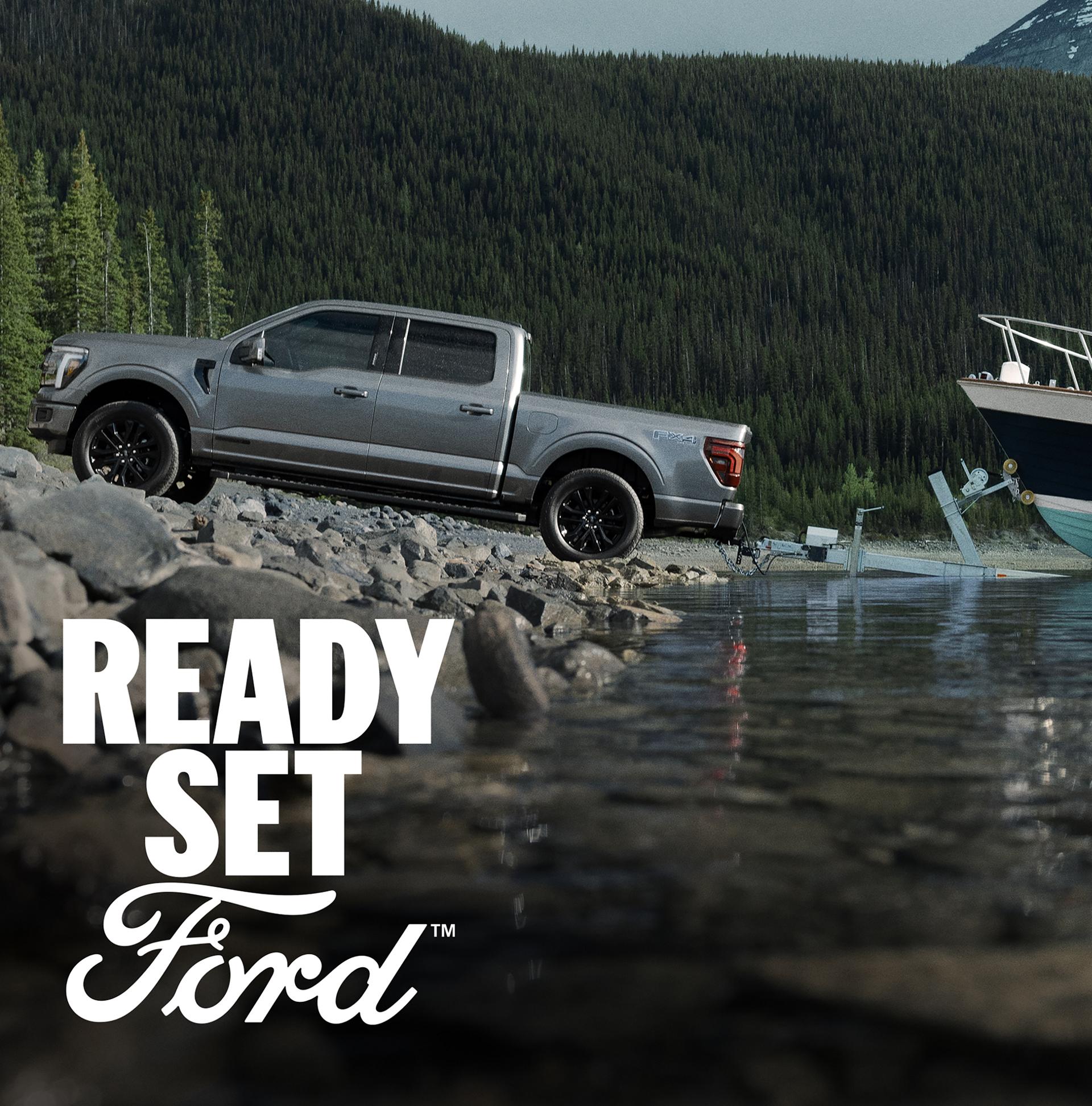 2026 Ford F-150® Lariat® with the FX4® Off-Road Package backing a boat into the water at a boat launch