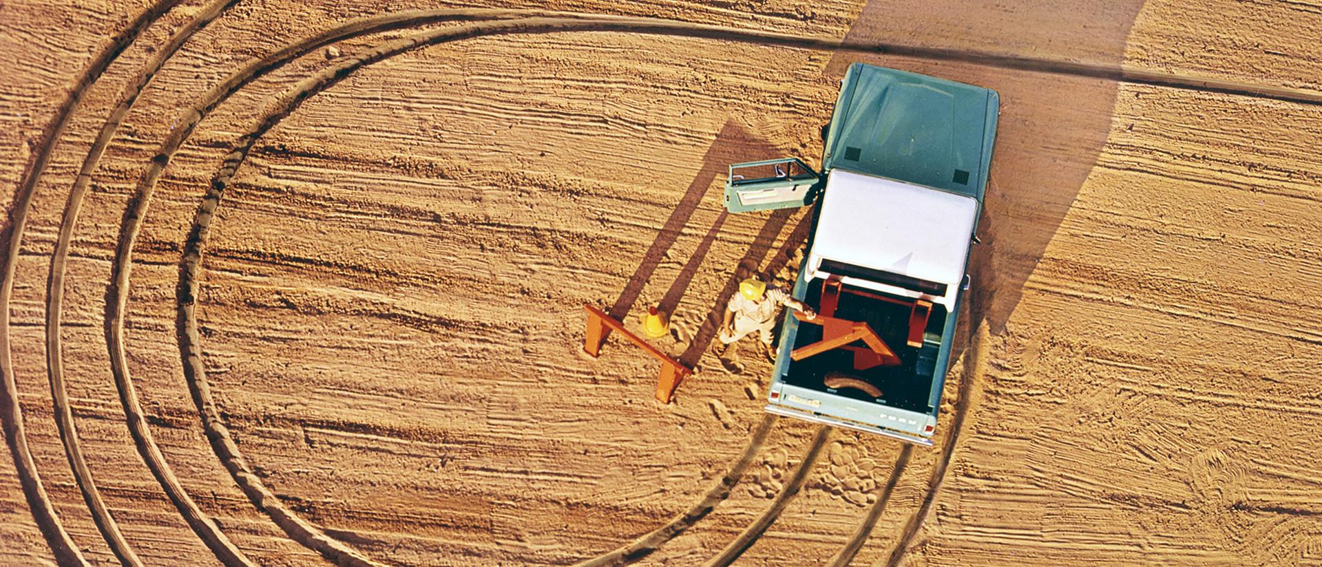 A 1969 Ford Bronco® model being driven showing circular tire tracks from above