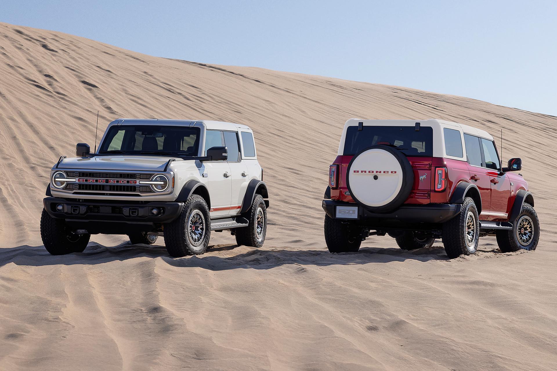 Two 2026 Ford Bronco® Outer Banks® SUVs with the available 60th Anniversary Package parked on a sandy expanse