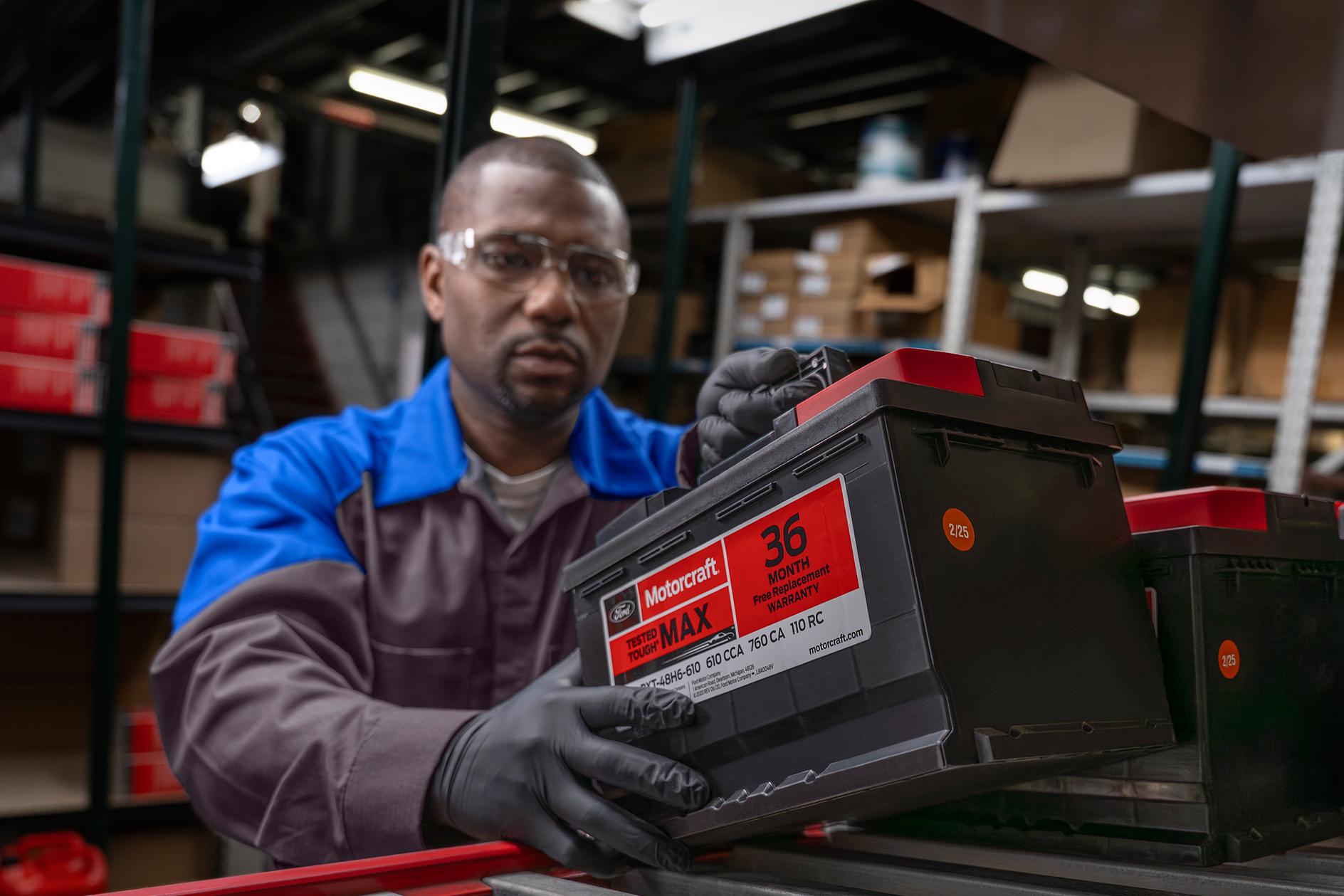 A Ford Service technician pulls a new battery from the shelf