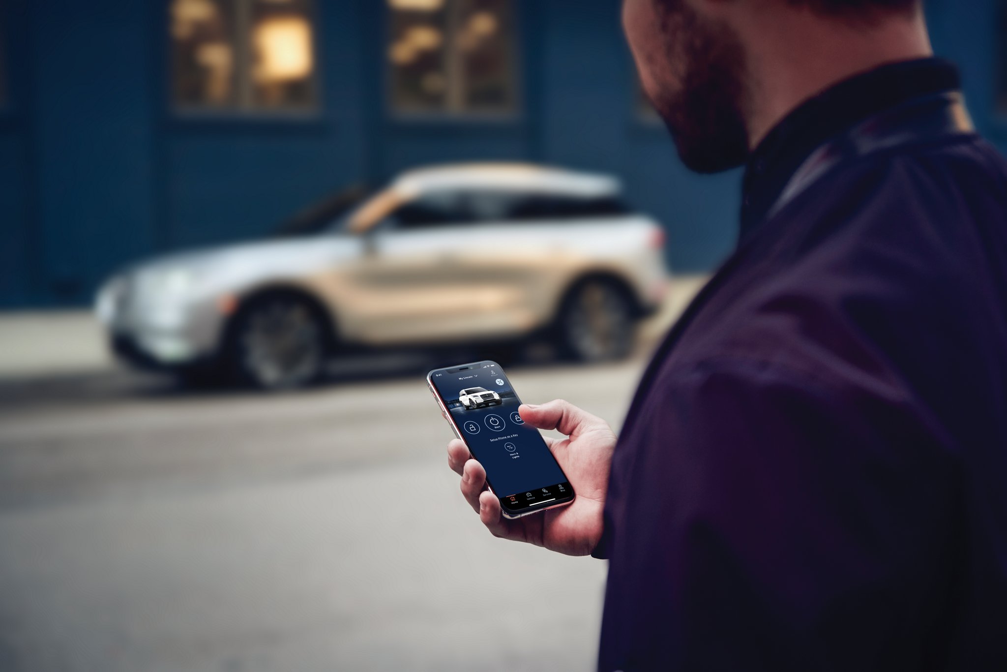 A person uses the Lincoln app to start a Lincoln SUV located across the street