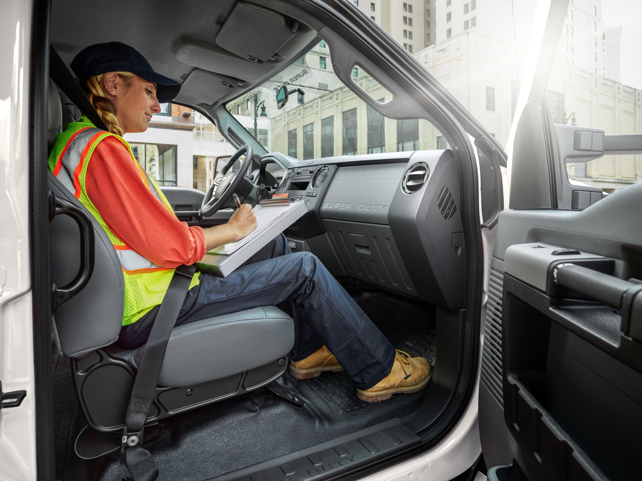 Worker writing on clipboard in passenger seat of 2026 Ford F-750® Crew Cab in Oxford White