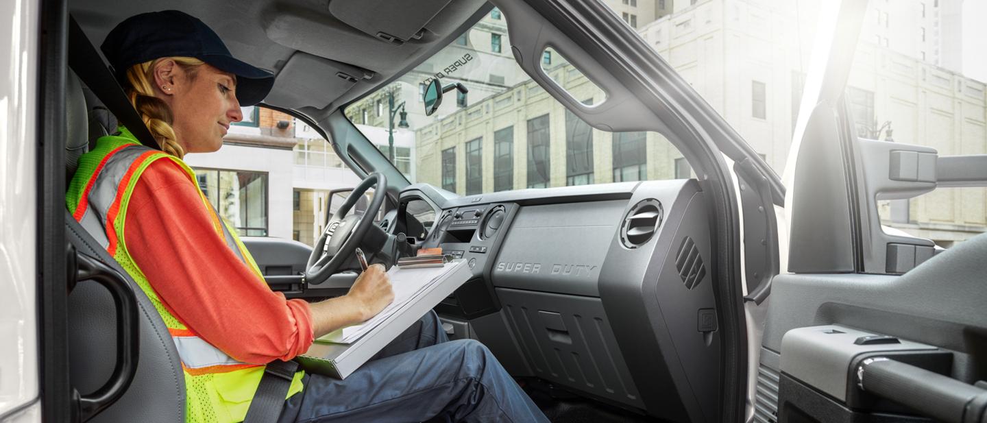 Worker writing on clipboard in passenger seat of 2026 Ford F-750® Crew Cab in Oxford White