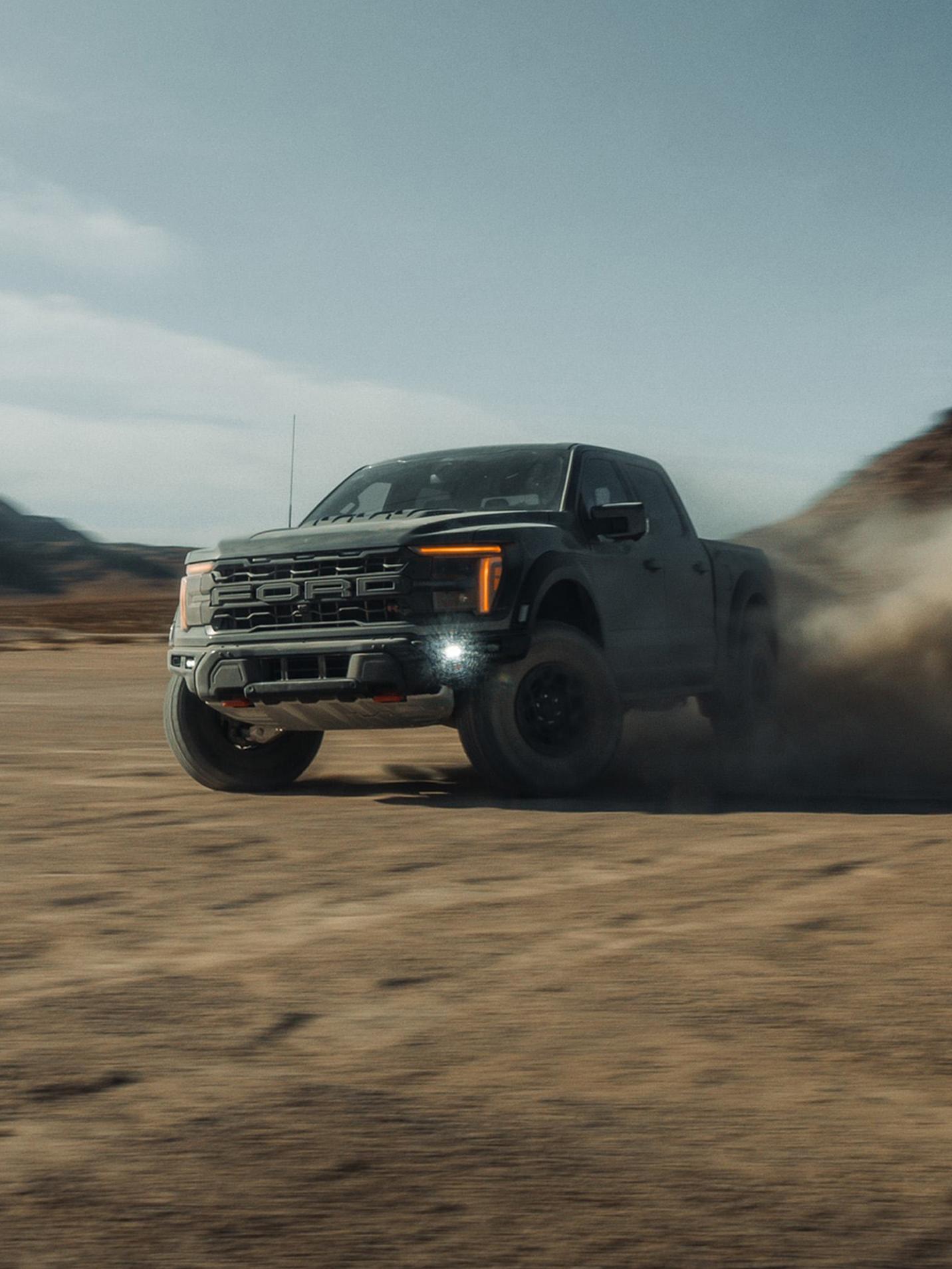 2027 Ford F-150® Raptor R™ truck being driven in the desert kicking up a cloud of sand