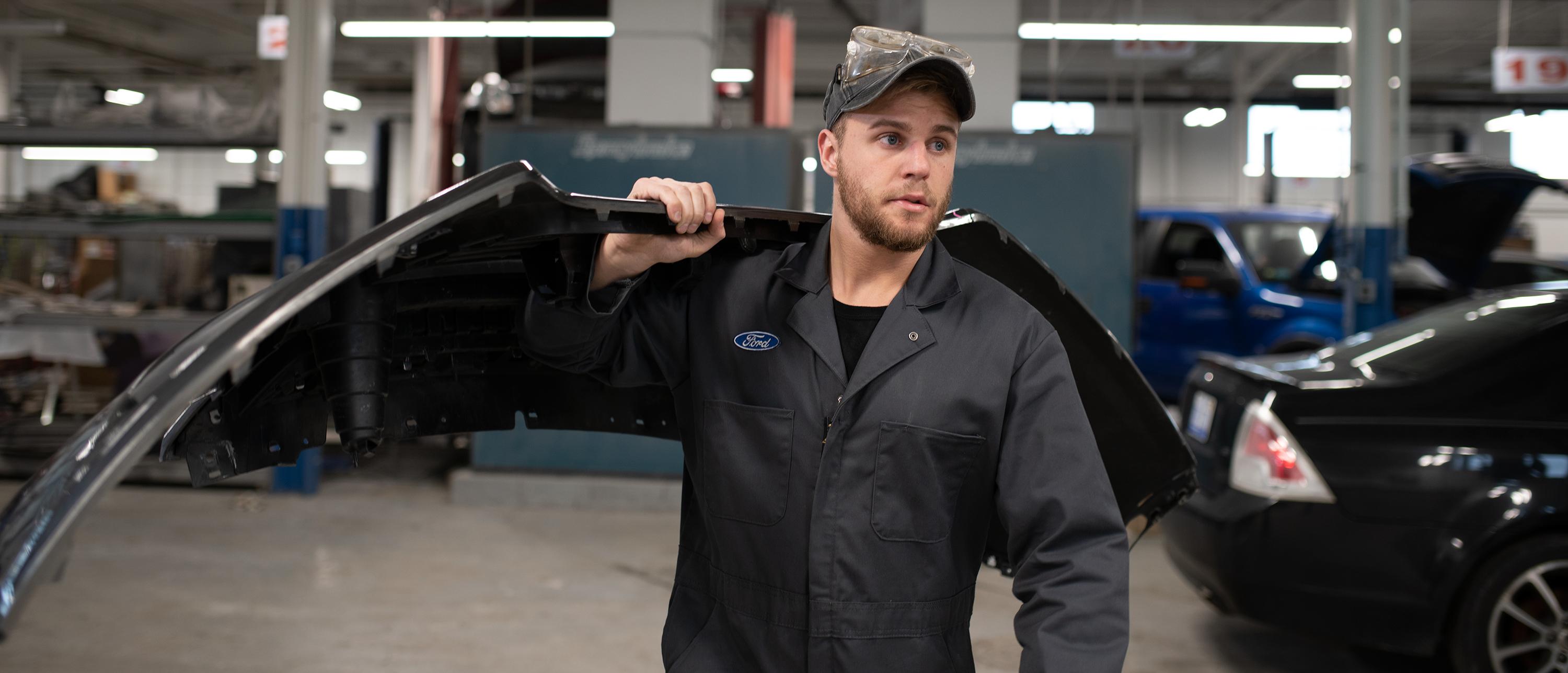 A Ford technician in a Certified Center carries a Ford part