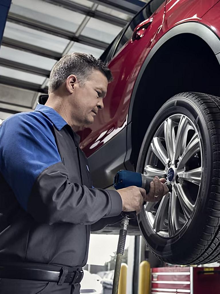 A Ford service technician tightens down a wheel