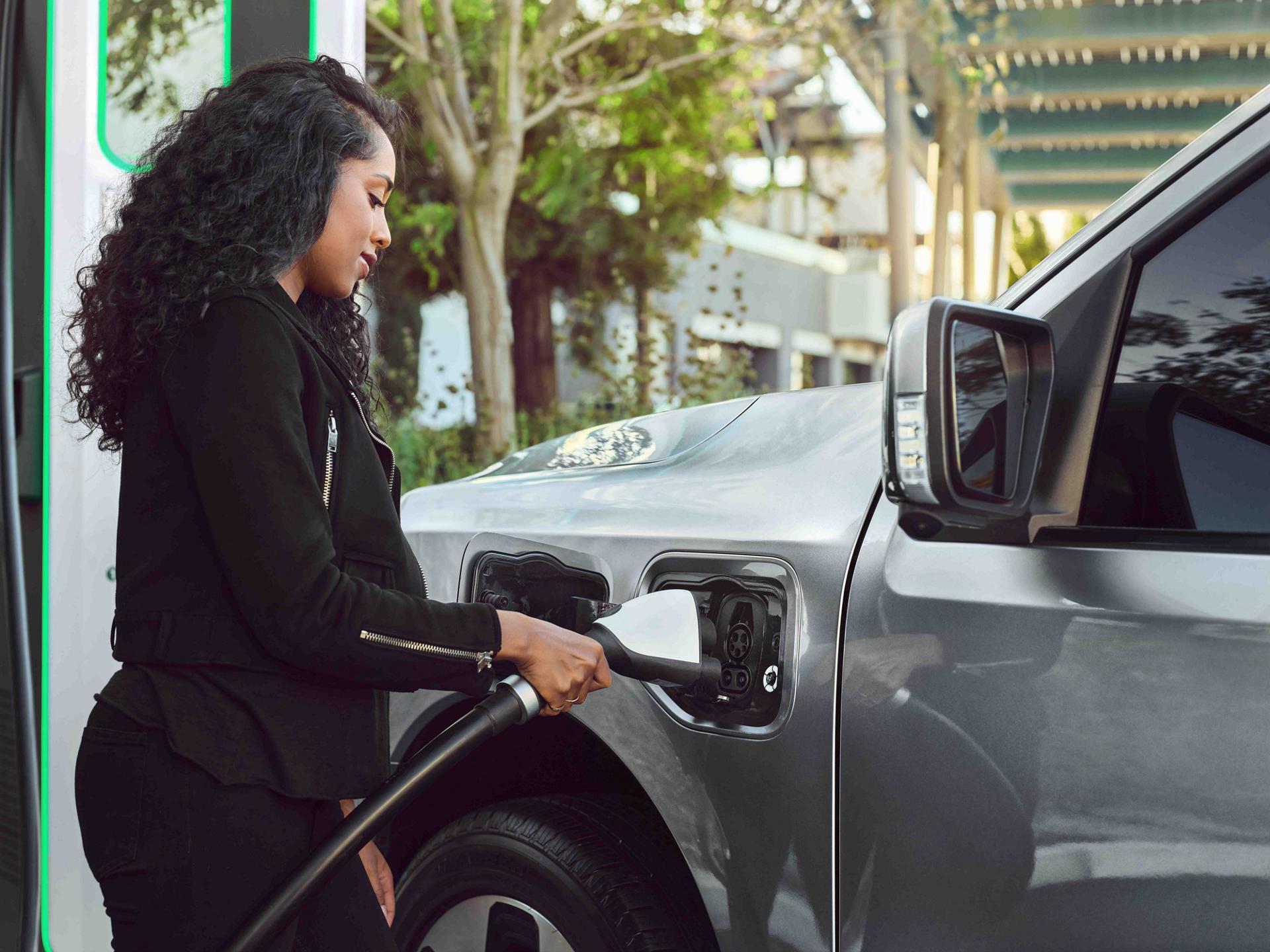 A woman plugging a charger into the charge port on a 2025 Ford F-150® Lightning® pickup