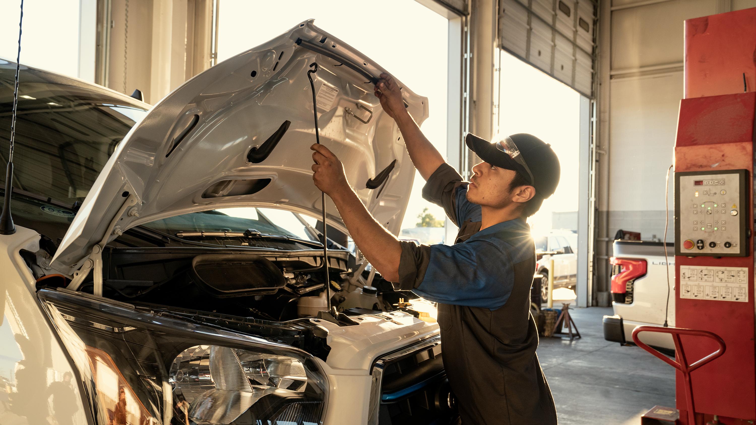 A Ford Service technician opens the hood of a Ford vehicle in a service garage