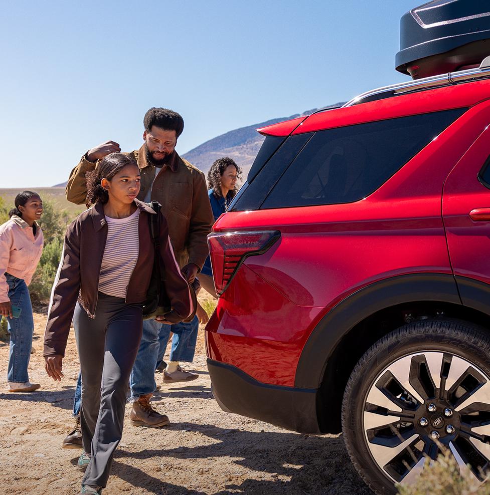 A family walking around the rear of a parked 2026 Ford Explorer® SUV in the desert