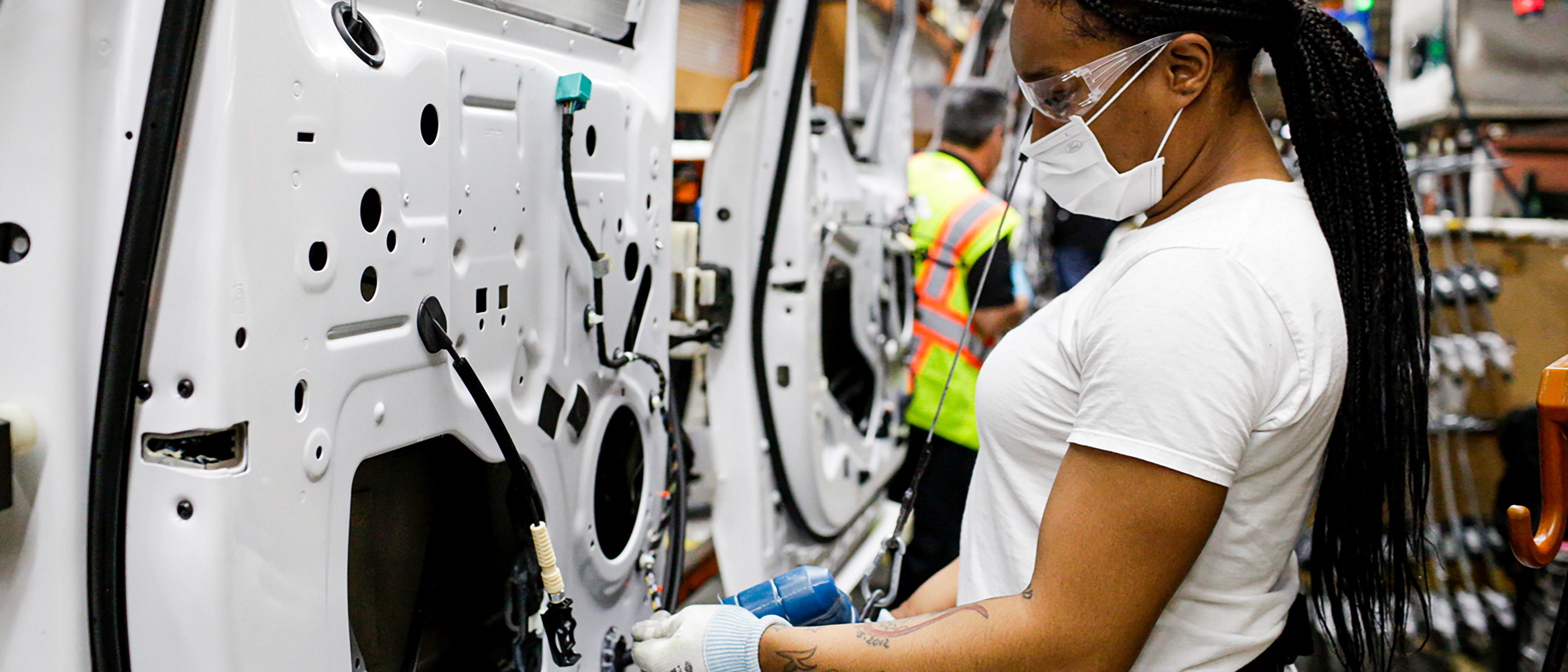 People working on vehicle doors on assembly line