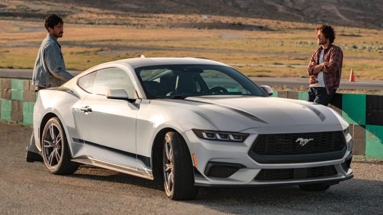 2025 Ford Mustang® EcoBoost® coupe with available Wheel and Stripe package parked on a racecourse near people