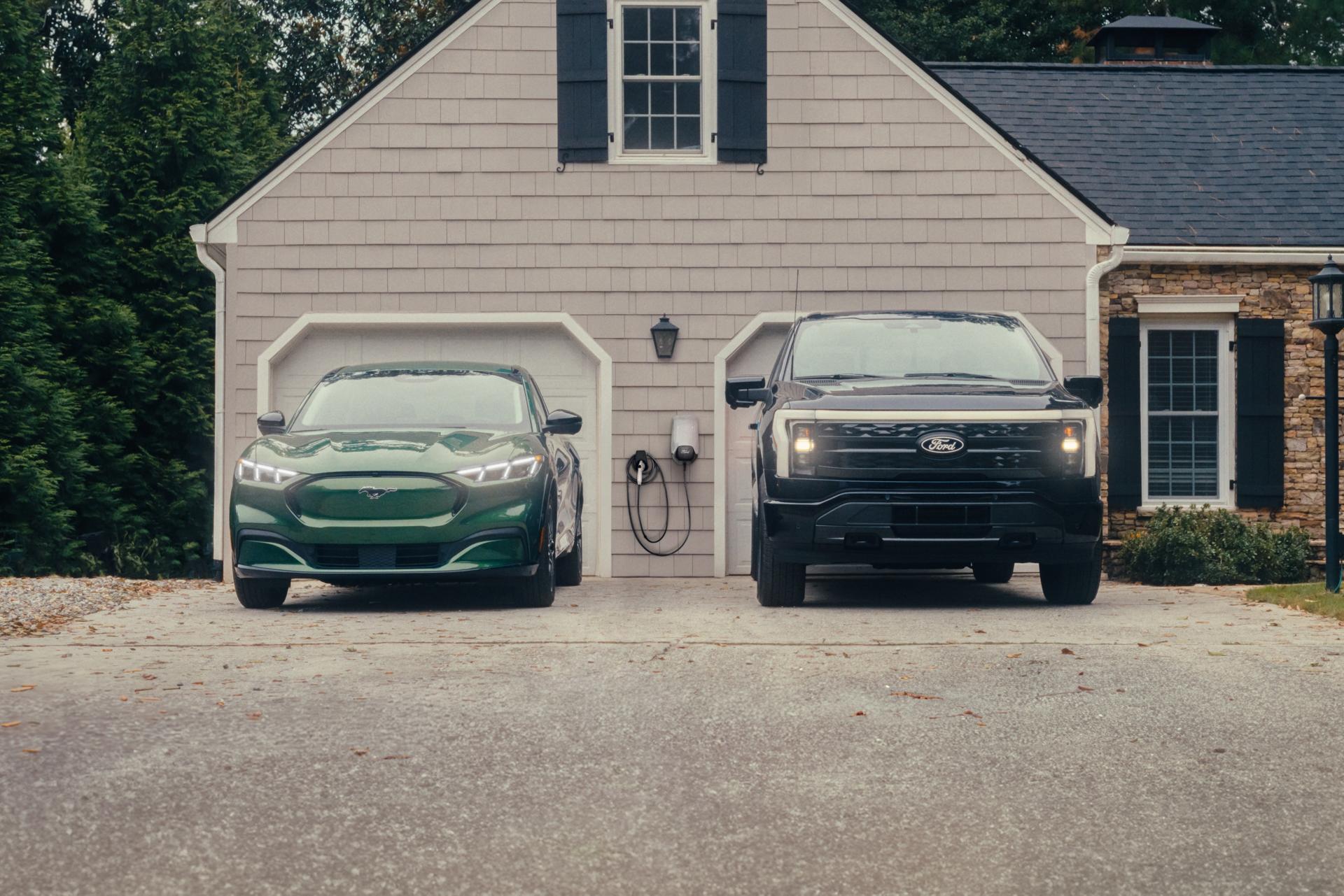 Ford Mustang Mach-E® SUV and Ford F-150® Lightning® parked in the driveway in front of a double-car garage