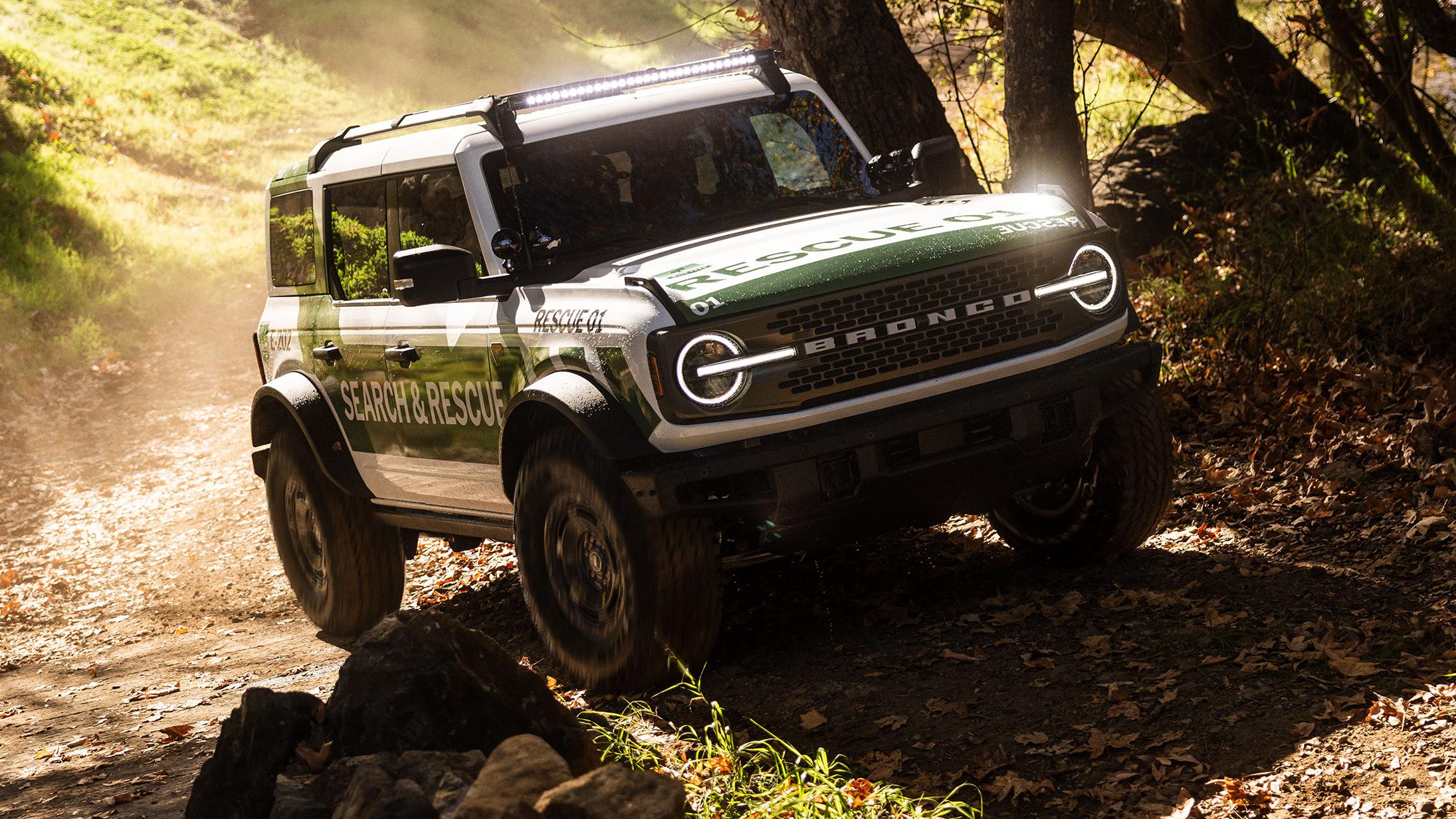 A white with green graphics Ford Bronco Badlands equipped as search and rescue vehicle driving on an incline