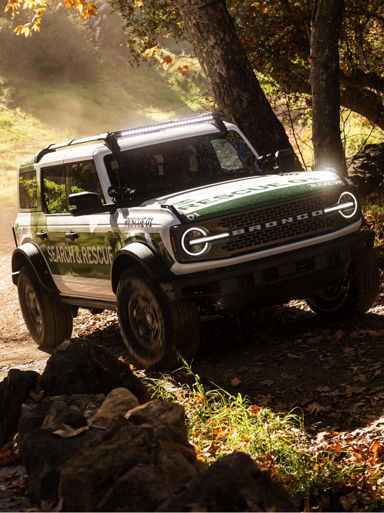 A white with green graphics Ford Bronco Badlands equipped as search and rescue vehicle driving on an incline