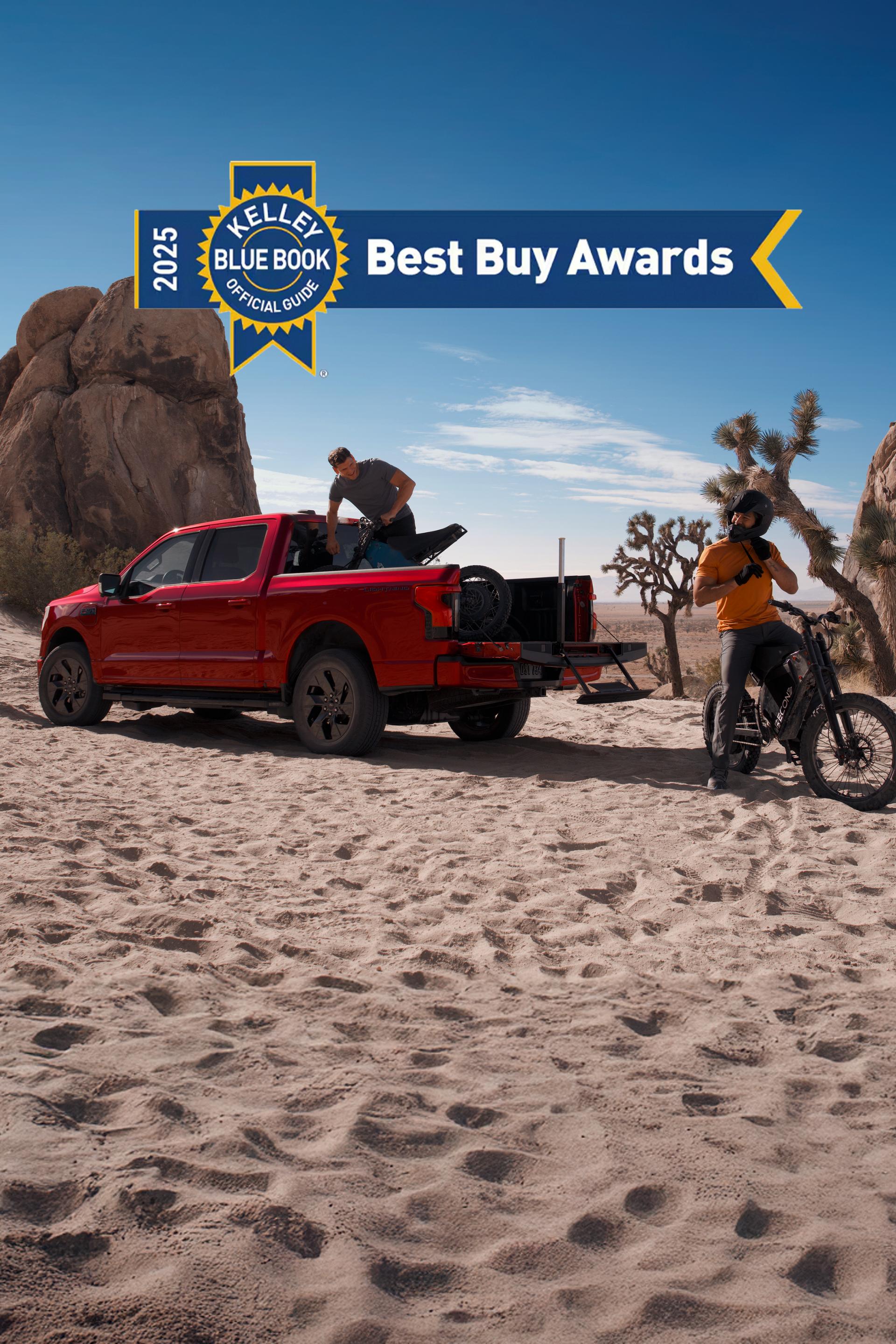 A red 2025 Ford F-150® Lightning® truck parked in the desert with a man getting a mountain bike out of the truck bed. Another man is sitting on his mountain bike nearby.