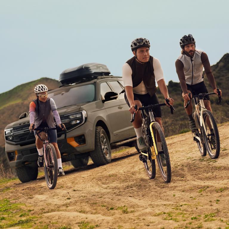 Three people riding bicycles near a parked 2026 Ford Expedition® Tremor® SUV