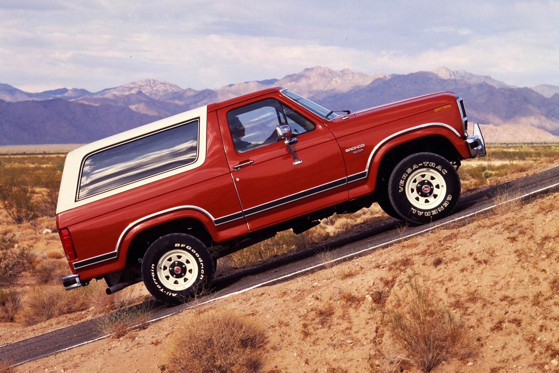 A two-tone 1984 Ford Bronco® model being driven up a steep incline
