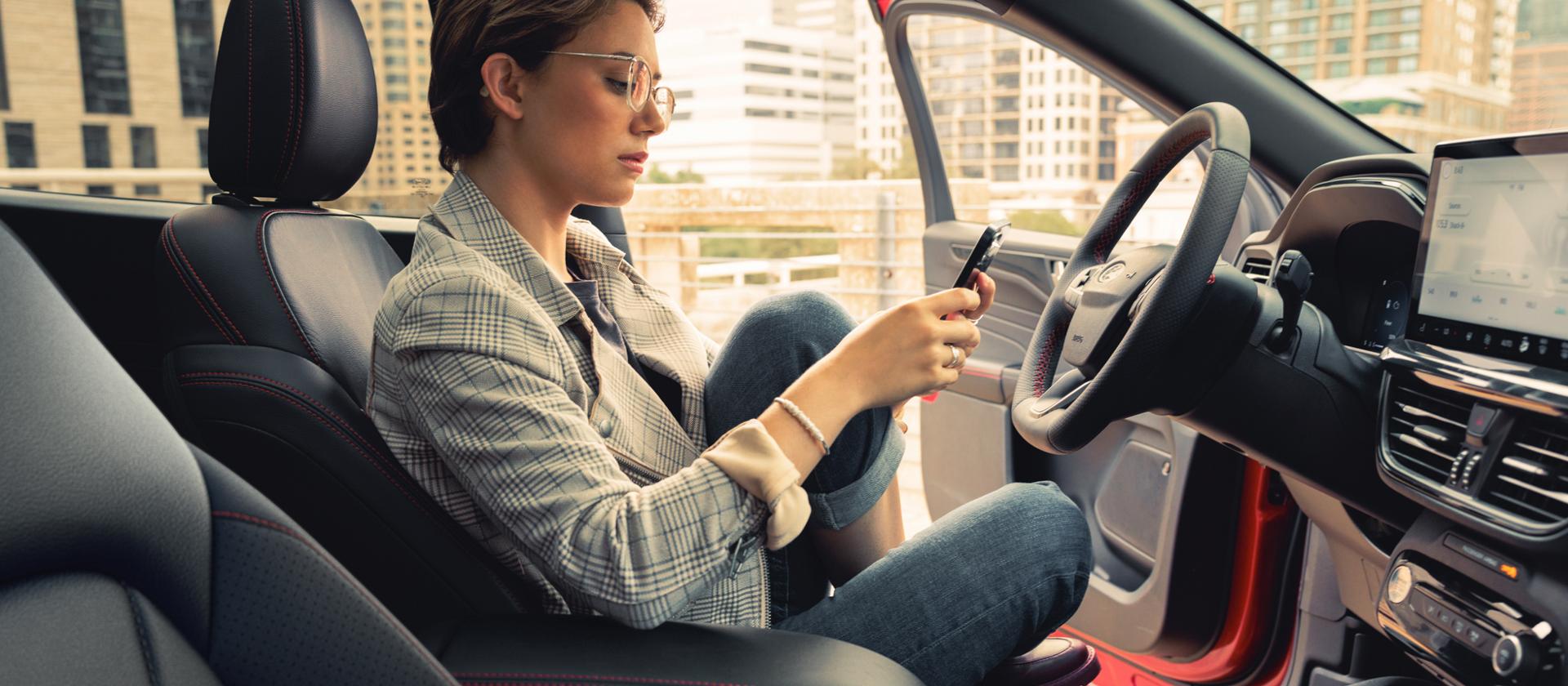 Woman using a phone in a parked 2026 Ford Escape® SUV