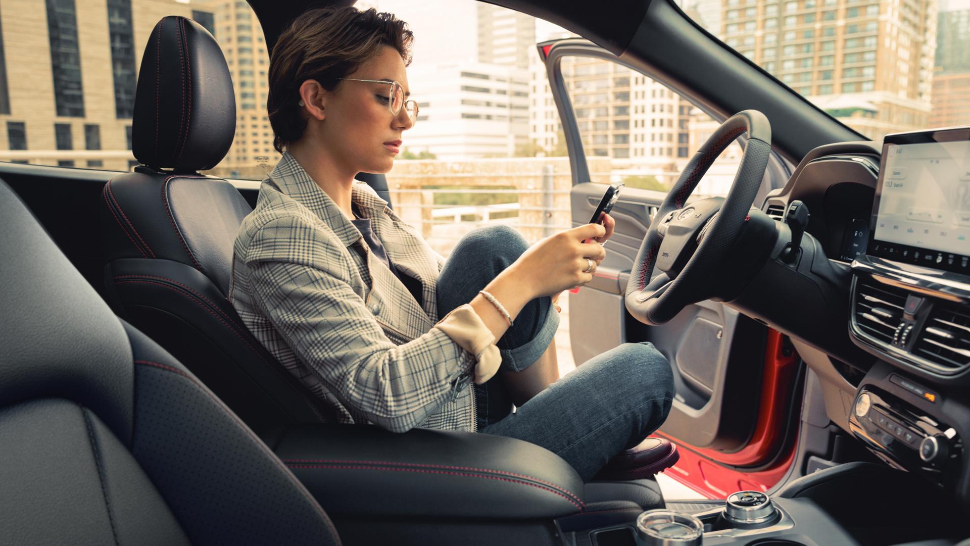 Woman looking at a phone in a parked 2026 Ford Escape® SUV