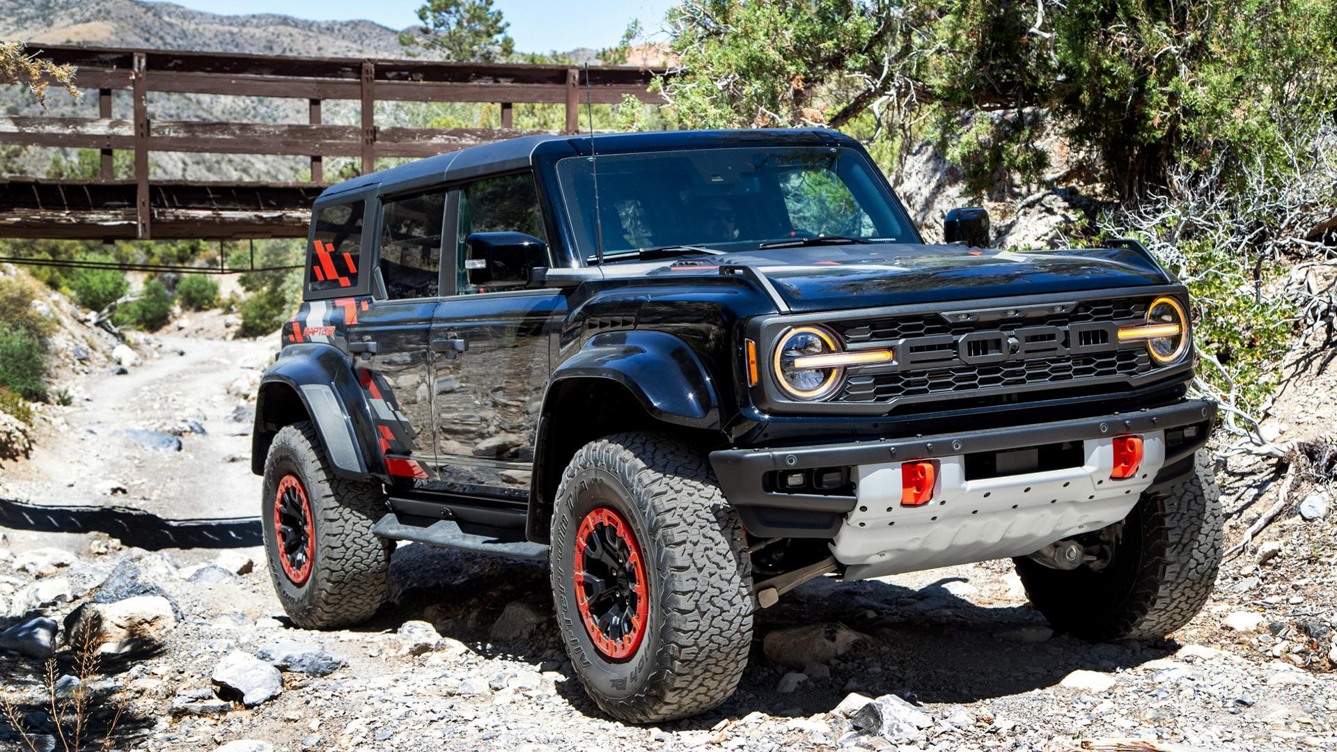 A 2026 Ford Bronco® Raptor® SUV with the available Raptor Code Orange Appearance Package parked on a rocky streambed