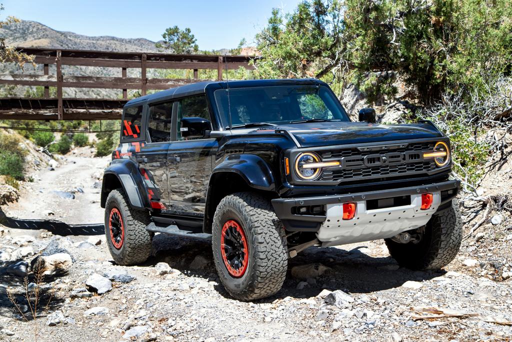 A 2026 Ford Bronco® Raptor® SUV with the available Raptor Code Orange Appearance Package parked on a rocky streambed