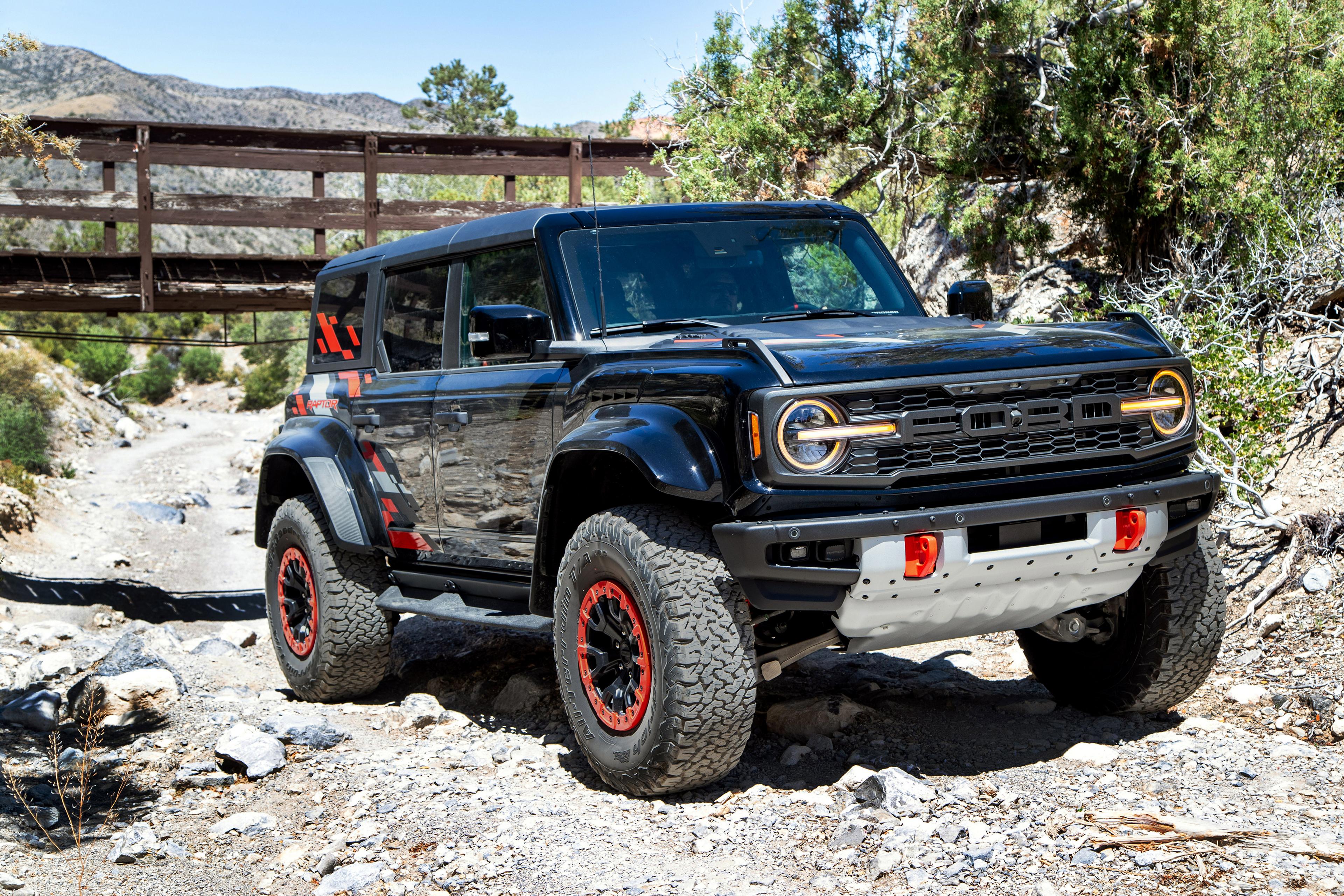 A 2026 Ford Bronco® Raptor® SUV with the available Raptor Code Orange Appearance Package parked on a rocky streambed