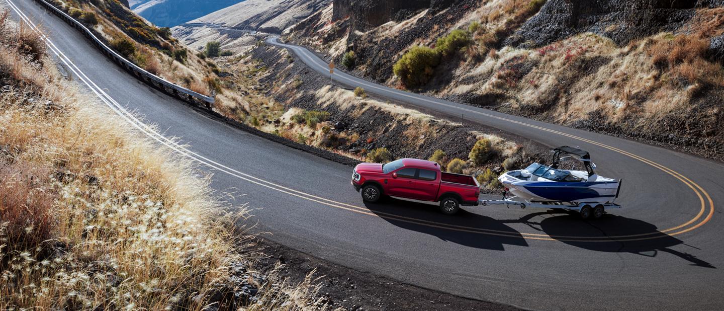 A 2026 Ford Ranger® truck pulling a speed boat on a winding, mountainous highway