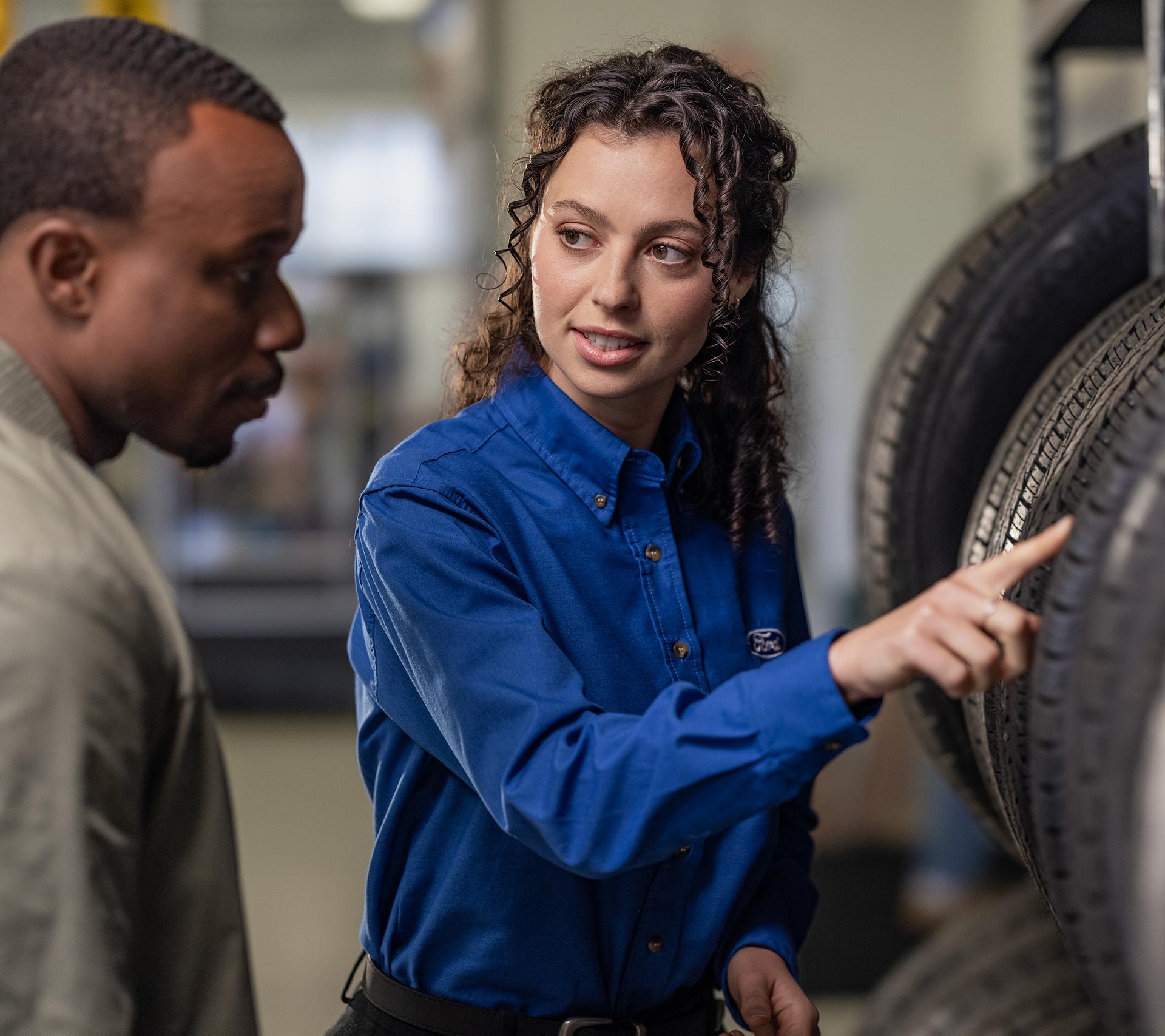 Ford dealership employee helping a customer find new tires