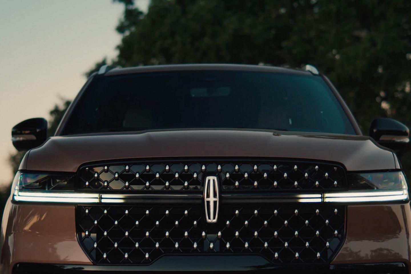 The grille of a parked 2025 Lincoln Navigator® SUV displays the lighting sequence of the Lincoln Embrace