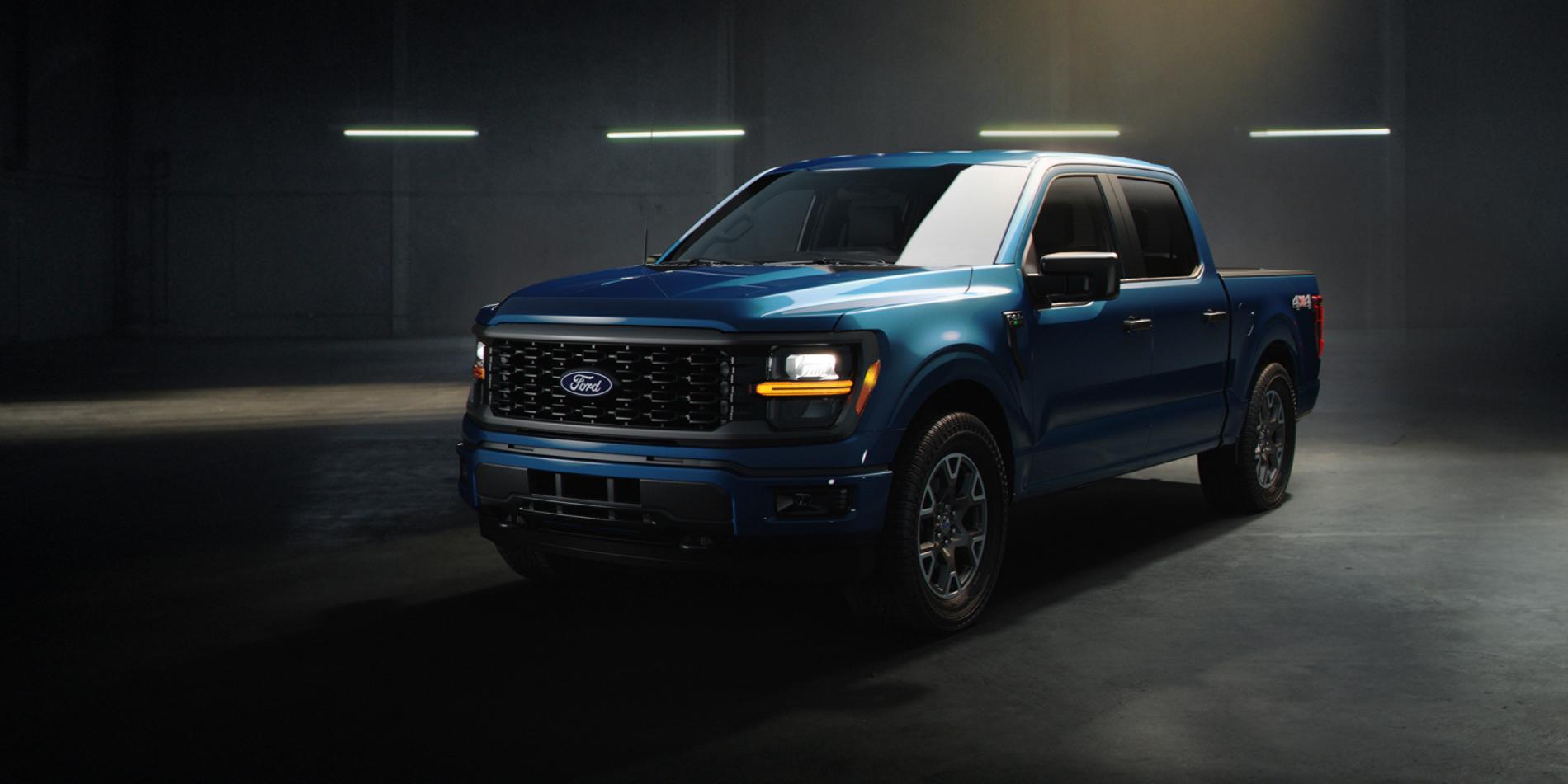 A blue 2025 Ford F-150 truck sitting in a warehouse environment with dramatic lighting