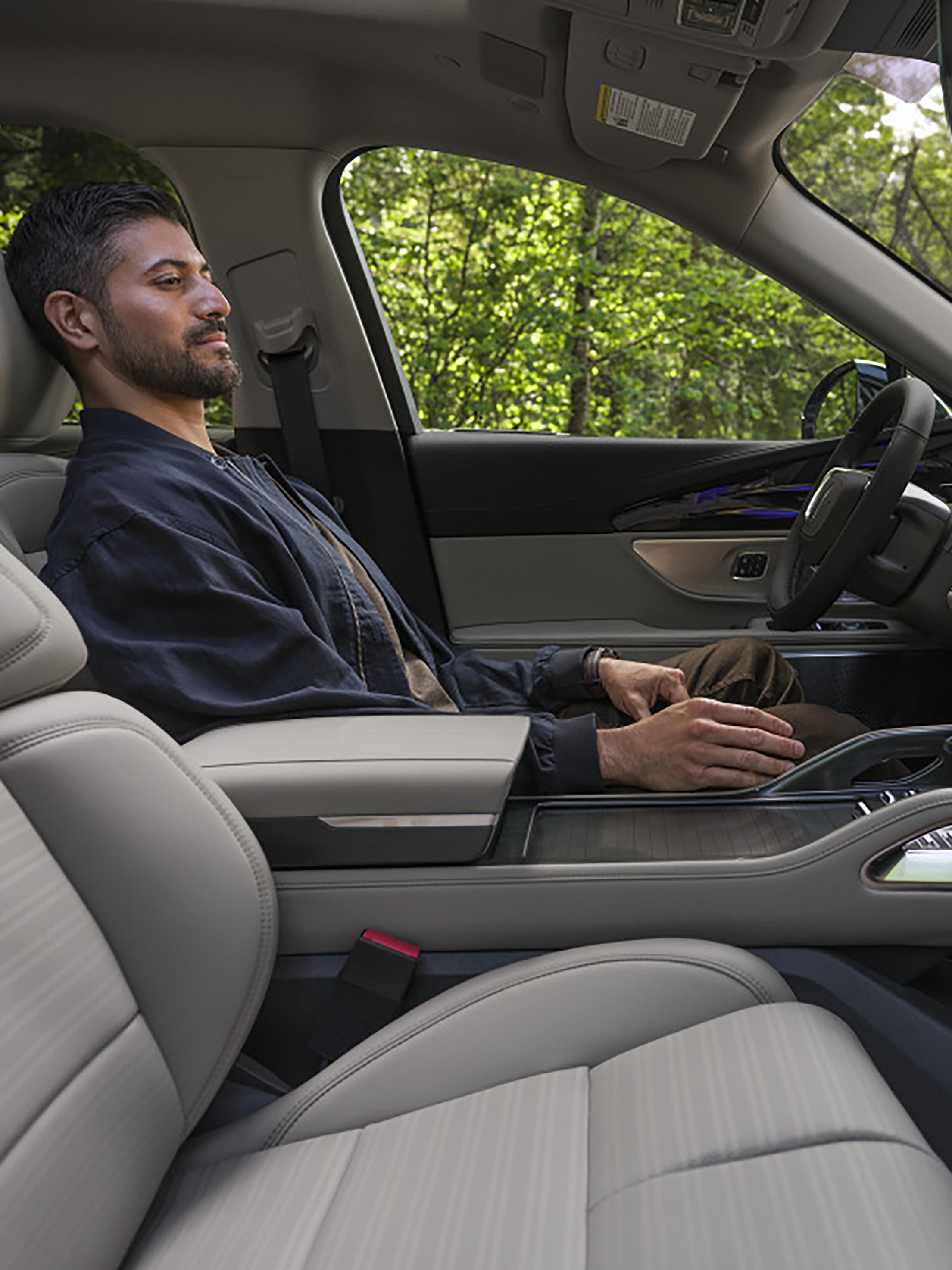 A person relaxes in the driver's seat of a Lincoln SUV