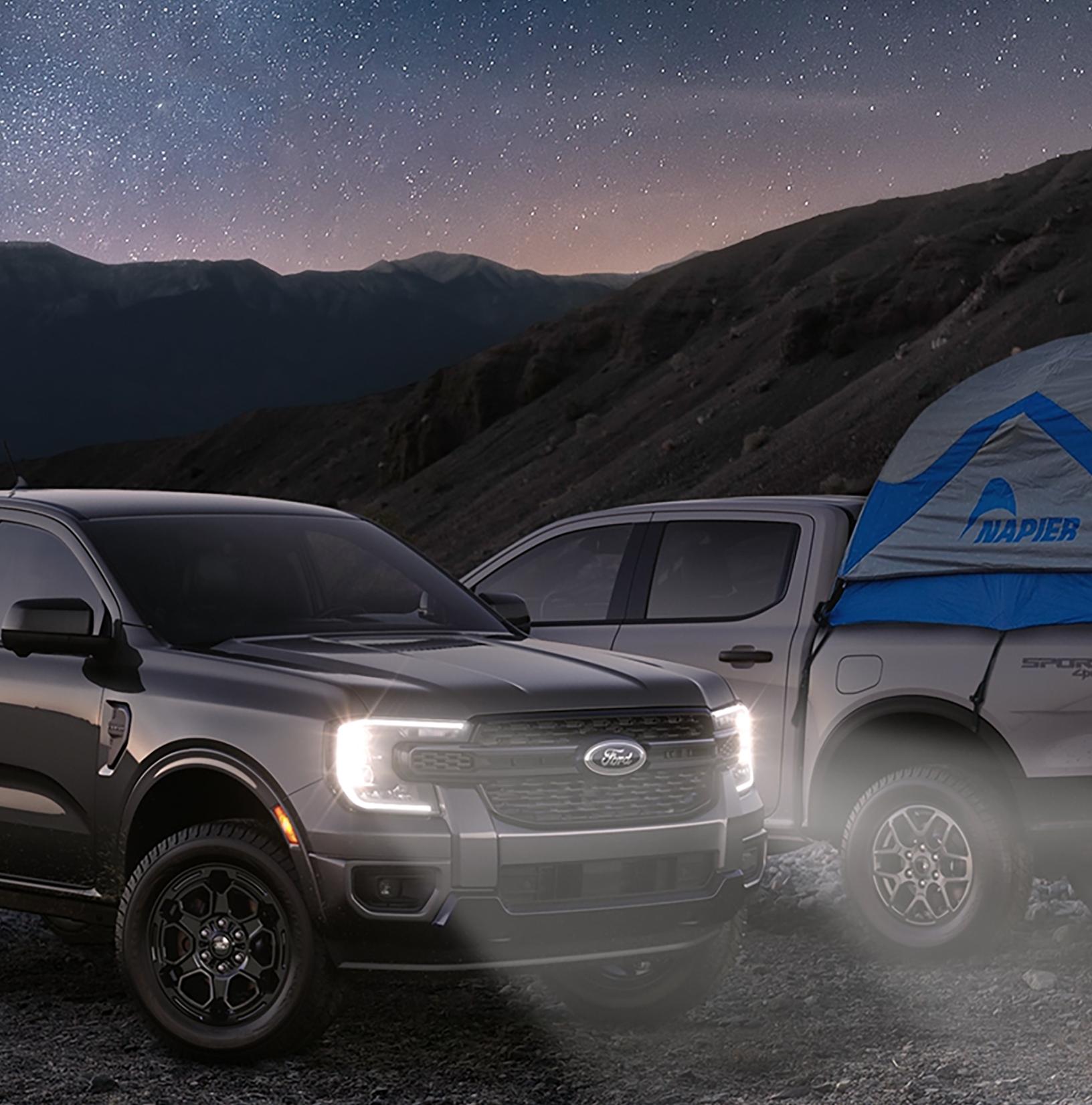 Two 2026 Ford Ranger® trucks parked under a starry, nighttime sky. One of them with a tent in the truck bed