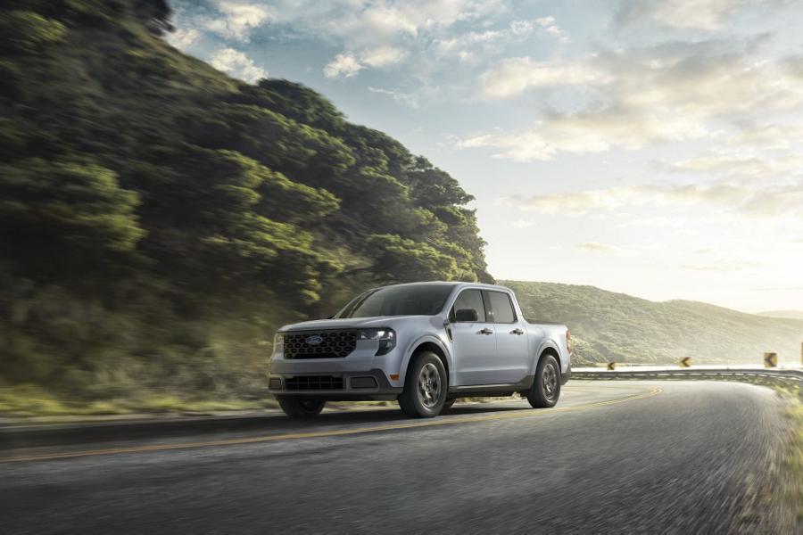 2026 Ford Maverick® pickup in Space White metallic being driven on a winding highway near a mountain lake