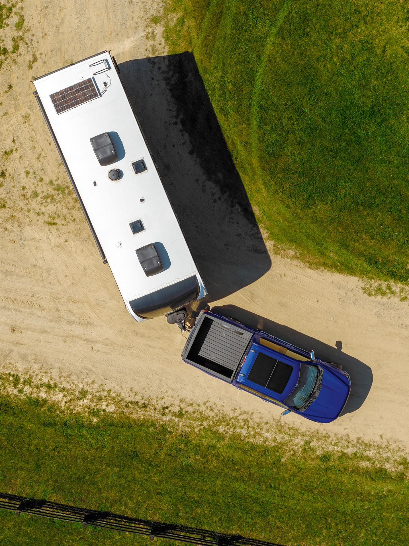 Overhead shot of a 2027 Ford F-150® truck in Argon Blue Metallic pulling a large camper