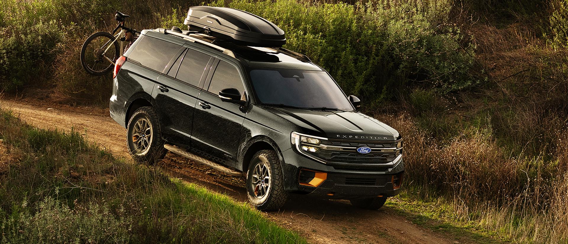2027 Ford Expedition® Tremor® SUV with optional equipment and available Ford accessories shown being driven on a dirt road