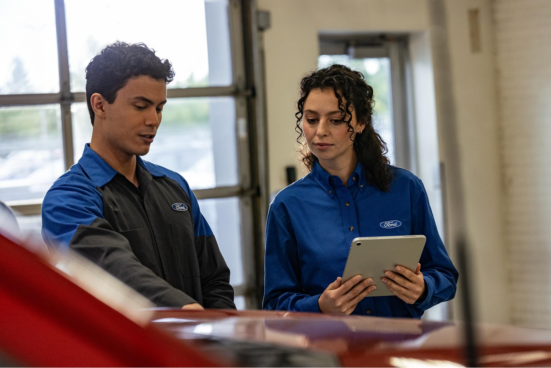 Two Ford Service Technicians inspect a vehicle