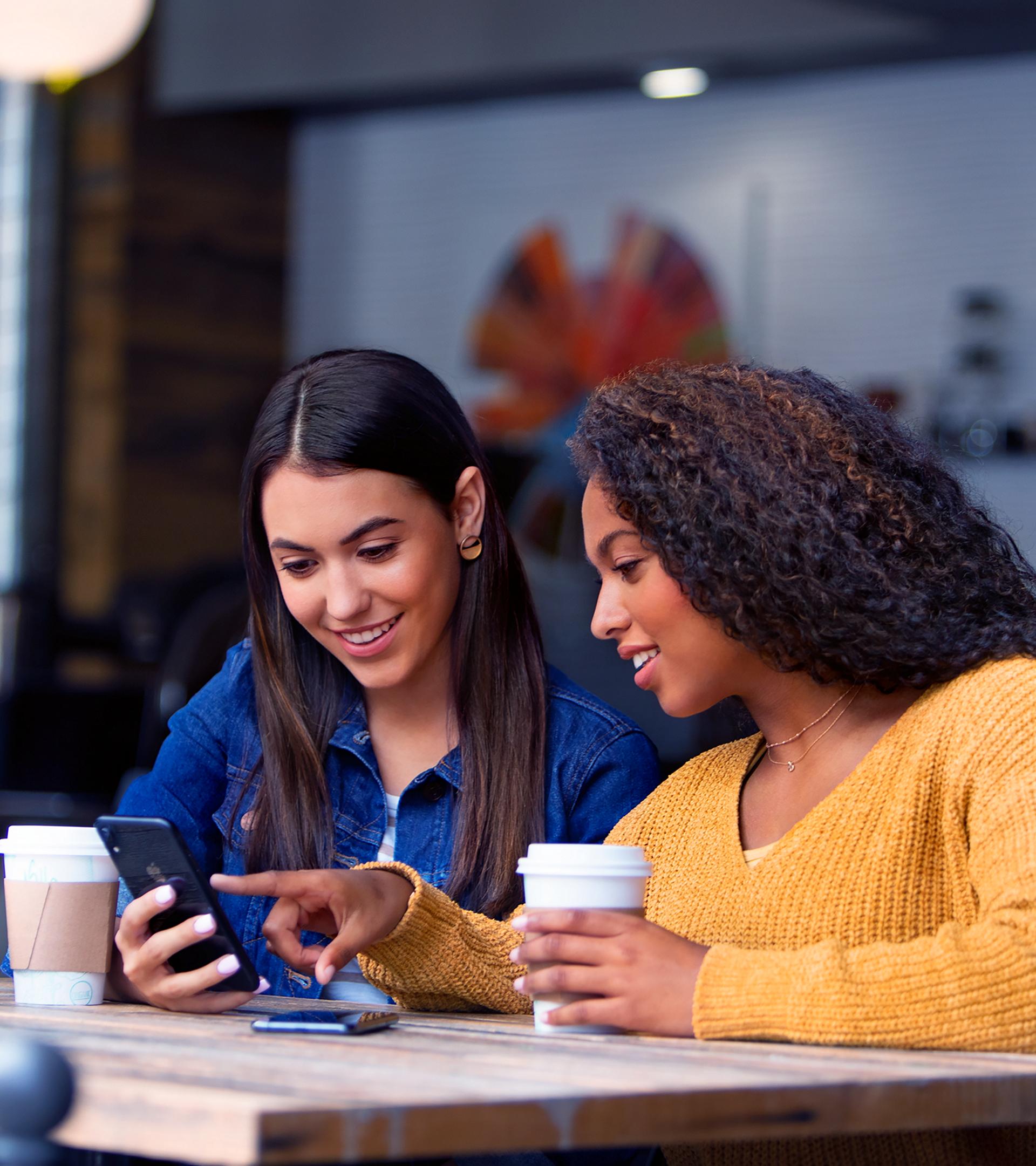 An owner shows their friend how 24/7 Live Support works while they sit outside a cafe