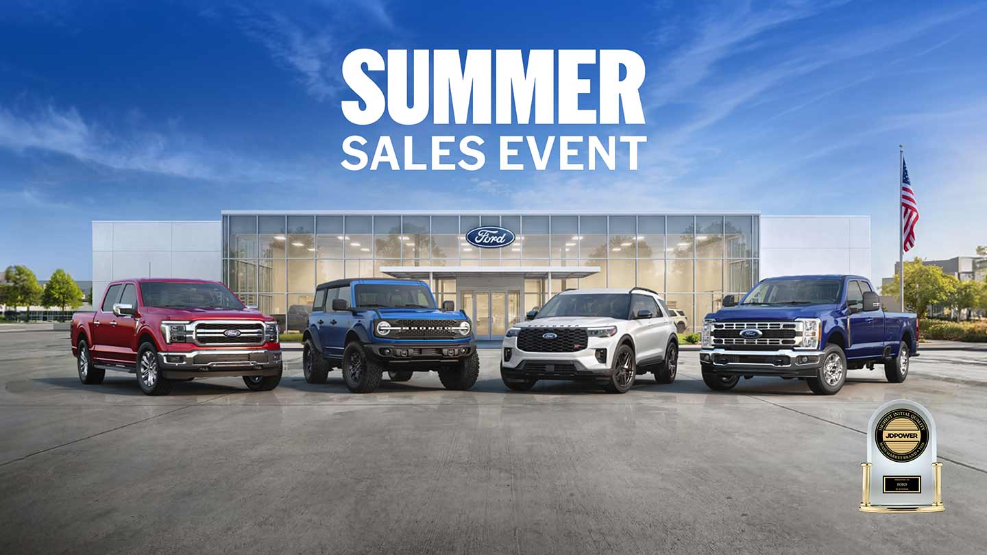 A line-up of Ford Trucks and SUVs parked in front of a Ford dealership