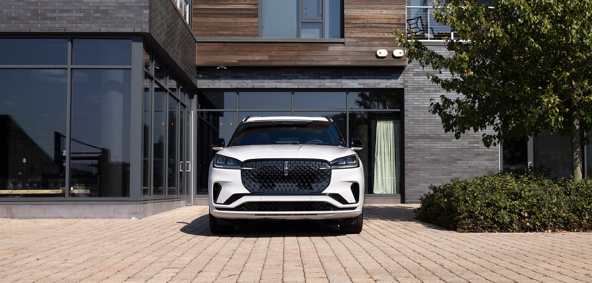 A 2025 Lincoln Aviator® SUV is parked in front of a modern home.